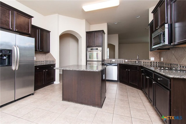 7010 Cokui Dr, Killeen, TX 76542 - kitchen featuring stainless steel appliances, light tile patterned floors, decorative backsplash, and dark stone counters