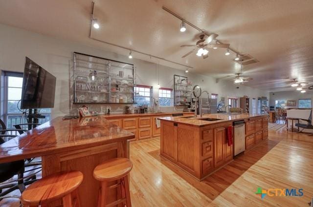 kitchen with dishwasher, sink, kitchen peninsula, light hardwood / wood-style floors, and a breakfast bar area