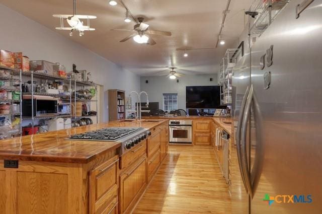 kitchen featuring a spacious island, sink, appliances with stainless steel finishes, and light hardwood / wood-style flooring