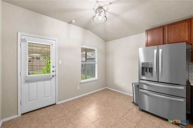 824 Starlight Dr, Temple, TX 76502 - kitchen with stainless steel fridge with ice dispenser, vaulted ceiling, baseboards, brown cabinetry, and light tile patterned flooring