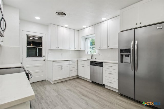 542 Williamsburg Pl, San Antonio, TX 78201 - kitchen with stainless steel appliances, a sink, light countertops, white cabinetry, and light wood finished floors