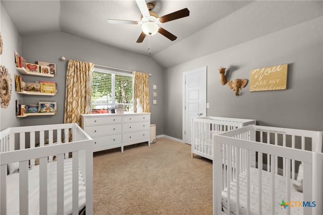 carpeted bedroom with lofted ceiling, ceiling fan, and a nursery area