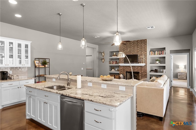 kitchen with white cabinets, sink, stainless steel dishwasher, a fireplace, and built in features