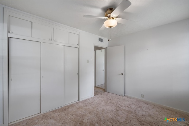 unfurnished bedroom with ceiling fan, light carpet, and a closet