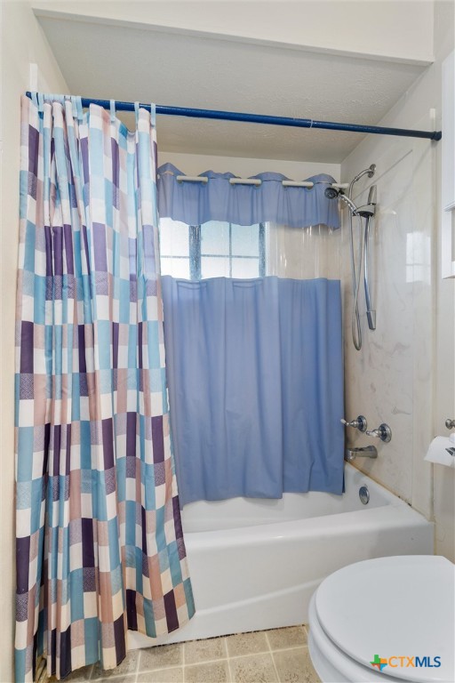 bathroom with tile patterned floors, toilet, and shower / bathtub combination with curtain