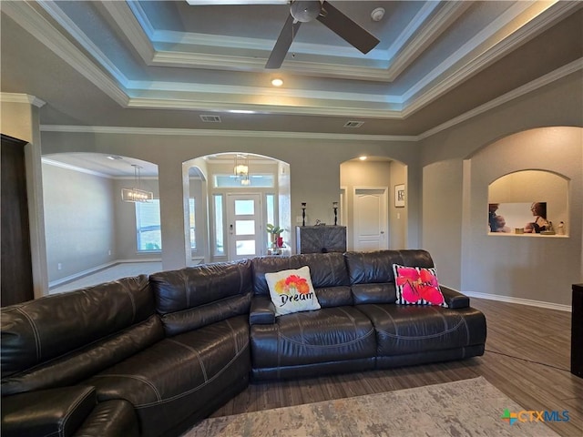 living area with arched walkways, a ceiling fan, wood finished floors, and a raised ceiling