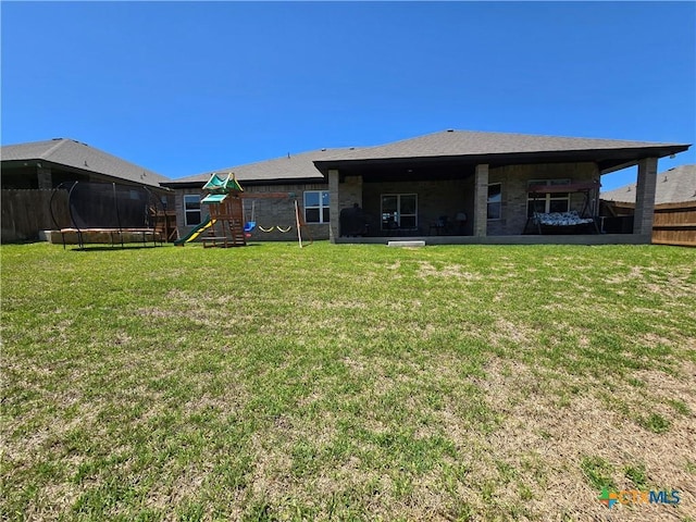 back of property featuring a lawn, a playground, fence, and a trampoline