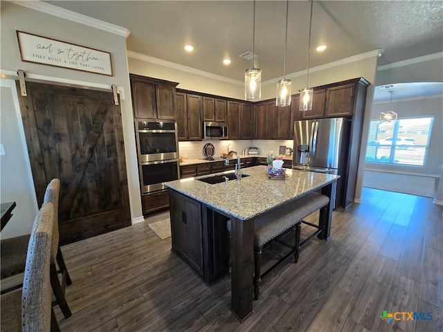 kitchen with stainless steel appliances, dark brown cabinetry, light stone counters, and a sink