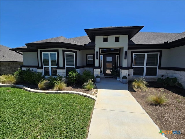 view of front of home with a shingled roof and a front yard