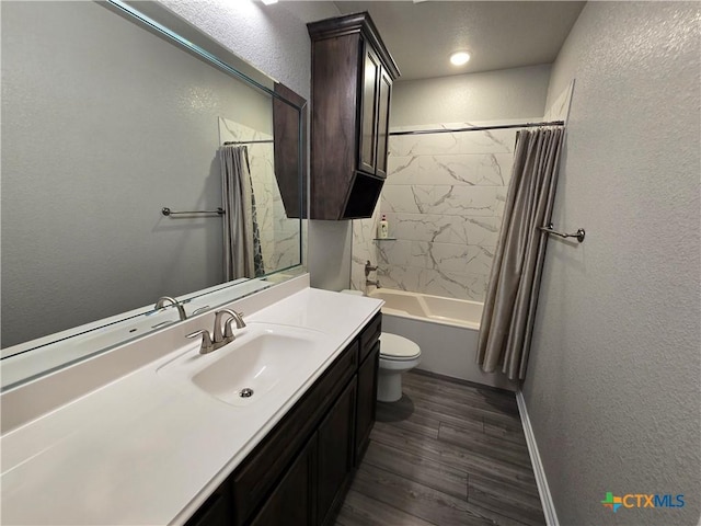 bathroom with vanity, a textured wall, wood finished floors, toilet, and shower / bath combo