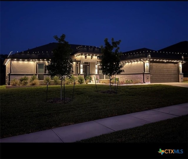 view of front facade featuring driveway, an attached garage, and a yard