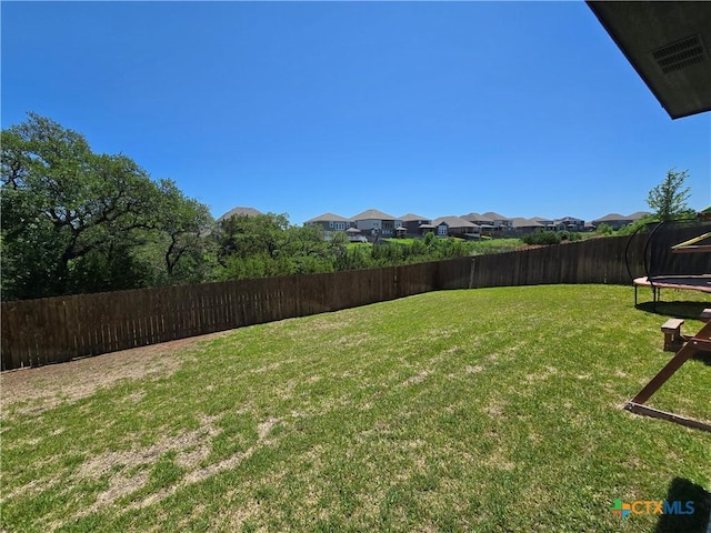 view of yard featuring a fenced backyard, a trampoline, and a residential view