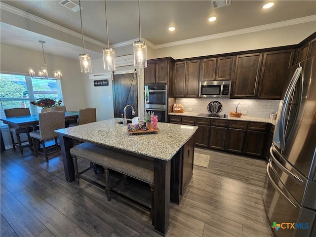 kitchen featuring a kitchen breakfast bar, dark brown cabinetry, visible vents, appliances with stainless steel finishes, and light stone counters