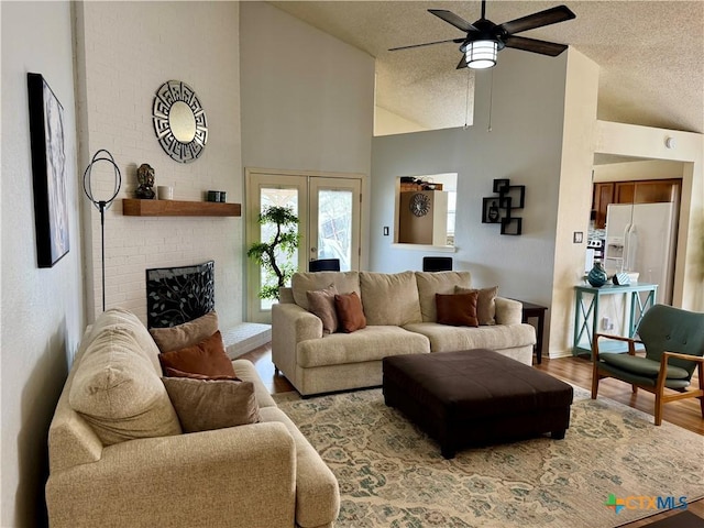 living room featuring ceiling fan, a fireplace, a textured ceiling, and wood finished floors