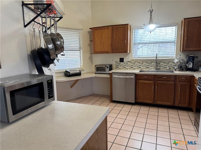 kitchen with light tile patterned floors, appliances with stainless steel finishes, a sink, light countertops, and backsplash