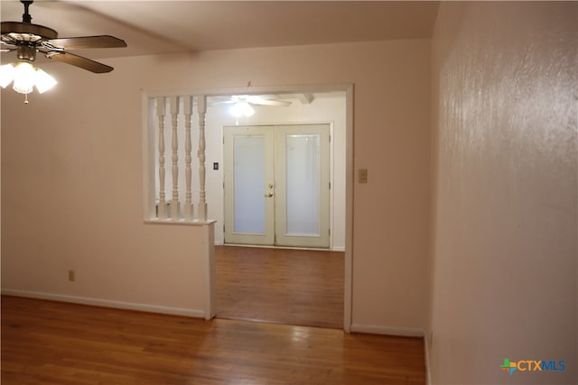 empty room with ceiling fan, hardwood / wood-style floors, and french doors