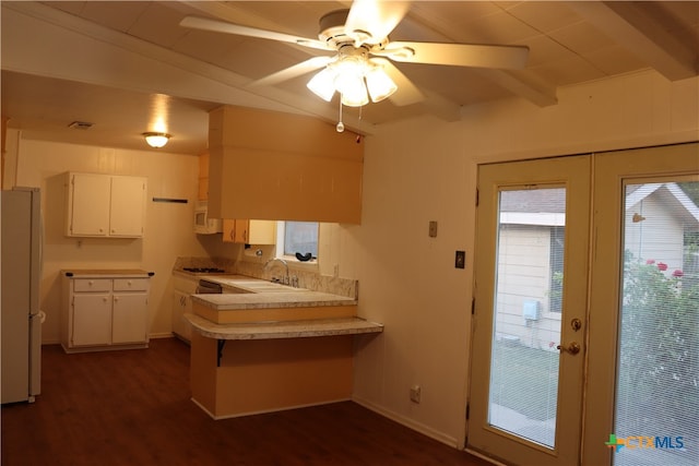 kitchen with kitchen peninsula, white appliances, dark wood-type flooring, sink, and white cabinets