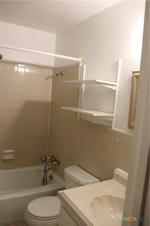 full bathroom featuring vanity, toilet, tiled shower / bath, and tile walls