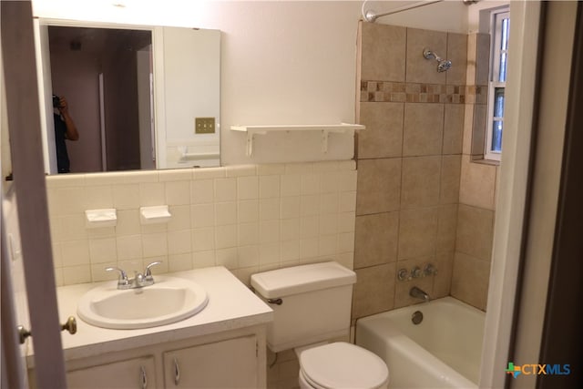 full bathroom with tiled shower / bath combo, toilet, decorative backsplash, vanity, and tile walls