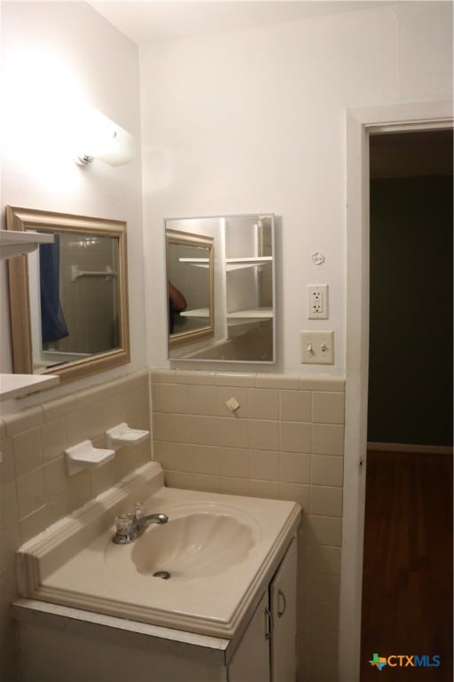 bathroom featuring wood-type flooring, vanity, and tile walls