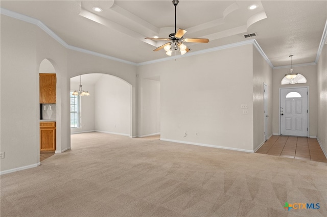 3102 Wisteria Ln, Killeen, TX 76549 - unfurnished living room featuring arched walkways, light carpet, ceiling fan, a chandelier, and a tray ceiling