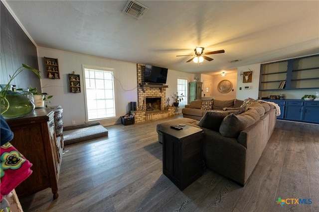 108 Elaine St, Victoria, TX 77904 - living area with visible vents, dark wood-type flooring, crown molding, a fireplace, and ceiling fan