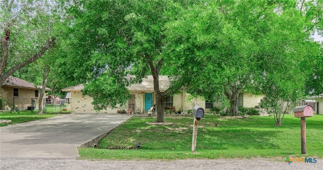 108 Elaine St, Victoria, TX 77904 - view of property hidden behind natural elements featuring concrete driveway, a front lawn, and brick siding