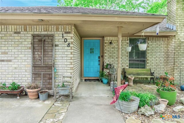 108 Elaine St, Victoria, TX 77904 - property entrance featuring brick siding, a porch, and a shingled roof