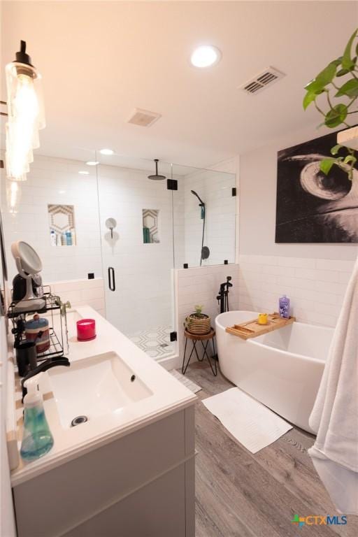 108 Elaine St, Victoria, TX 77904 - full bath featuring a shower stall, wood finished floors, visible vents, tile walls, and a freestanding tub