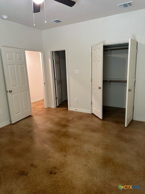 unfurnished bedroom with a closet, carpet flooring, and ceiling fan