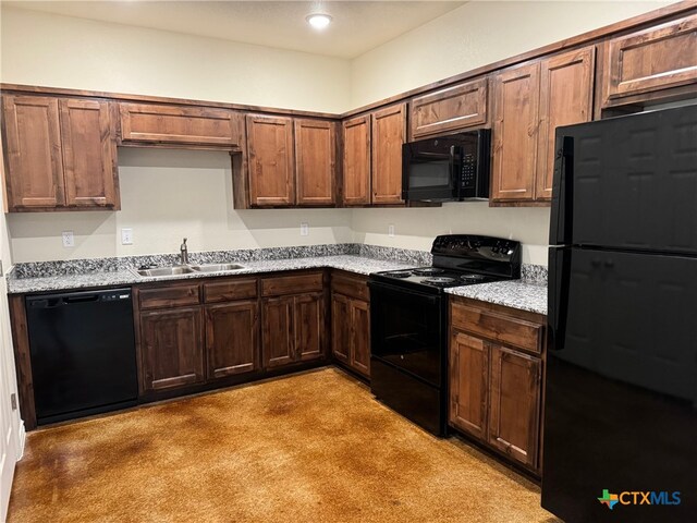 kitchen with black appliances, light stone countertops, sink, and light colored carpet