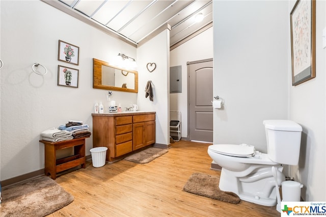 bathroom featuring wood-type flooring, vanity, toilet, and lofted ceiling