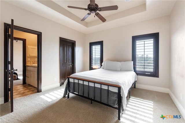 bedroom with light carpet, baseboards, and a tray ceiling