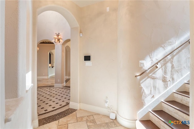 interior space featuring arched walkways, baseboards, and stone tile floors