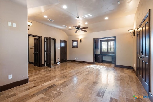 unfurnished room with lofted ceiling, light wood-type flooring, visible vents, and baseboards