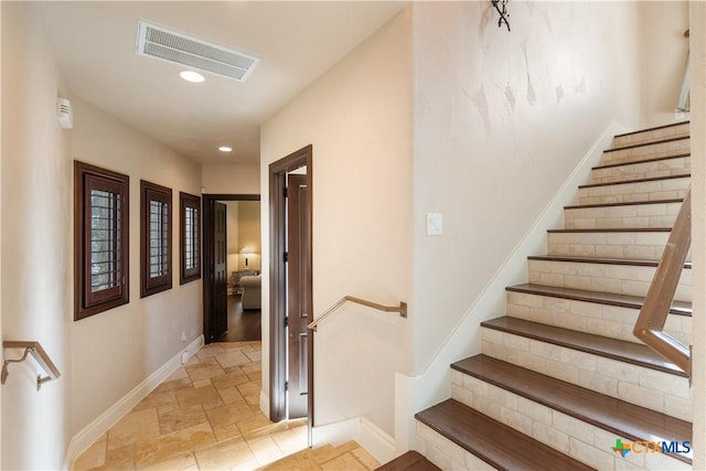 stairway with baseboards, visible vents, stone tile flooring, and recessed lighting