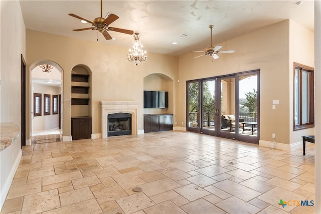 unfurnished living room featuring built in shelves, baseboards, a fireplace, and french doors