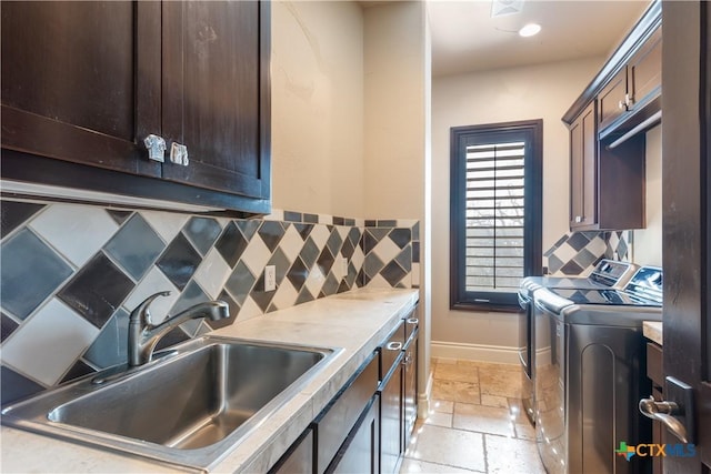 washroom with cabinet space, stone tile floors, baseboards, separate washer and dryer, and a sink