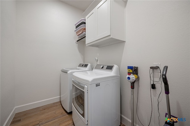 laundry room featuring baseboards, washer and clothes dryer, cabinet space, and light wood-style floors