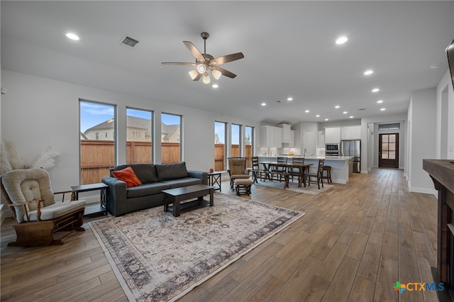 living room featuring recessed lighting, visible vents, hardwood / wood-style floors, ceiling fan, and baseboards