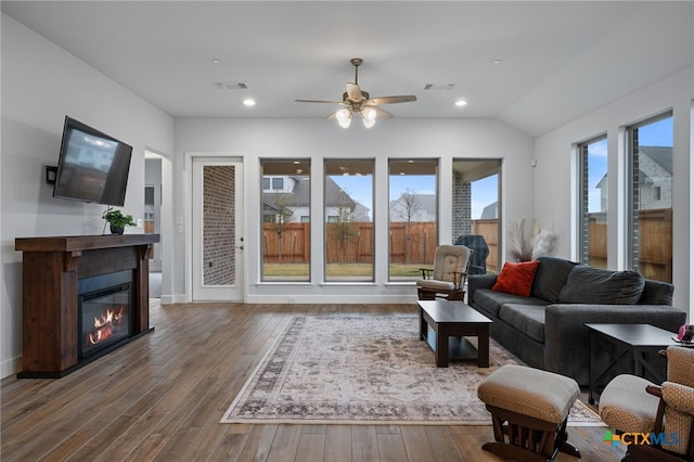 living area featuring a glass covered fireplace, wood-type flooring, visible vents, and recessed lighting