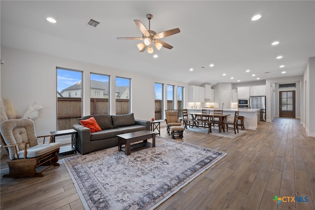 living area featuring recessed lighting, wood-type flooring, visible vents, ceiling fan, and baseboards