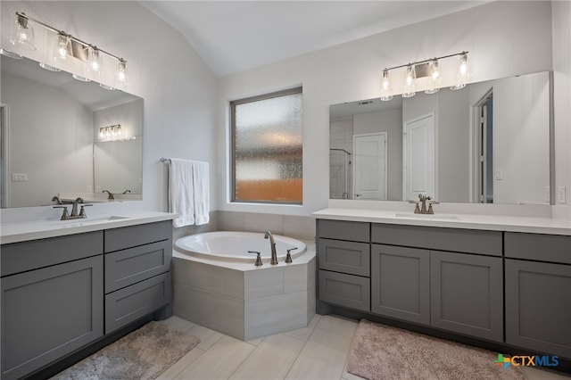 full bathroom featuring vaulted ceiling, a stall shower, a sink, and a bath