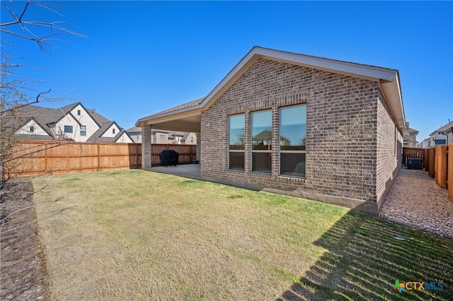 back of property featuring a fenced backyard, a patio, a lawn, and brick siding