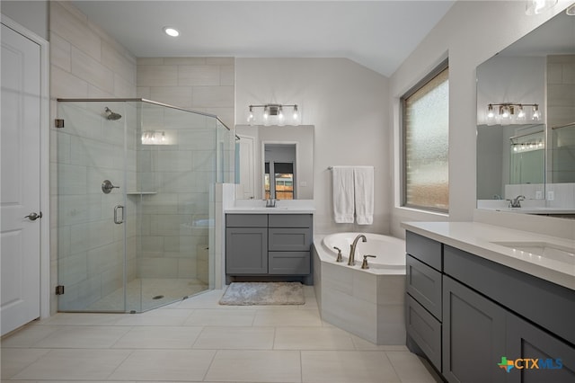 full bath with a garden tub, lofted ceiling, two vanities, a stall shower, and a sink