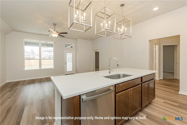 kitchen with dishwasher, sink, a kitchen island with sink, light wood-type flooring, and decorative light fixtures