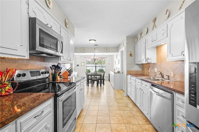 114 Berkshire Ln, Victoria, TX 77904 - kitchen featuring stainless steel appliances, light tile patterned floors, white cabinets, decorative backsplash, and a chandelier