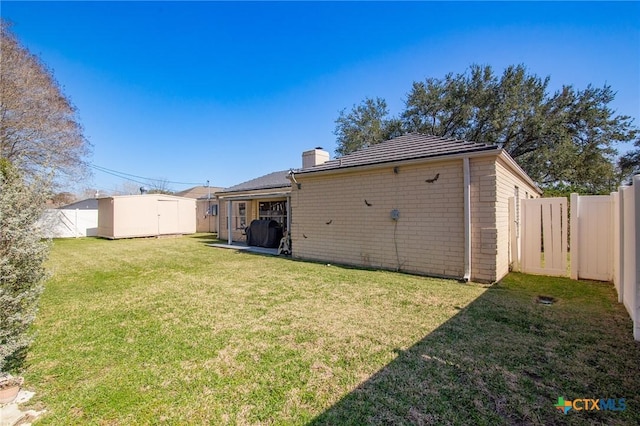 114 Berkshire Ln, Victoria, TX 77904 - rear view of house featuring brick siding, a fenced backyard, a storage shed, and a chimney