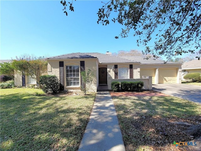 114 Berkshire Ln, Victoria, TX 77904 - view of front facade with concrete driveway, brick siding, a garage, a front lawn, and a chimney