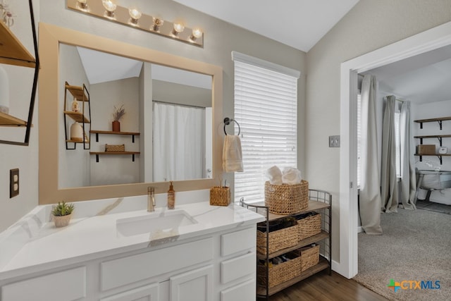 bathroom featuring vaulted ceiling, hardwood / wood-style floors, and vanity